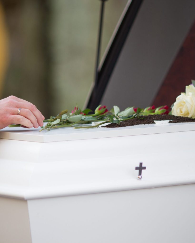A closeup shot of a person hand on a casket with a blurred background