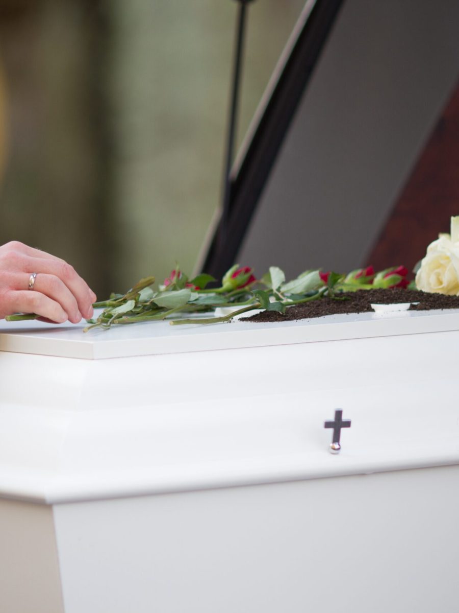 A closeup shot of a person hand on a casket with a blurred background