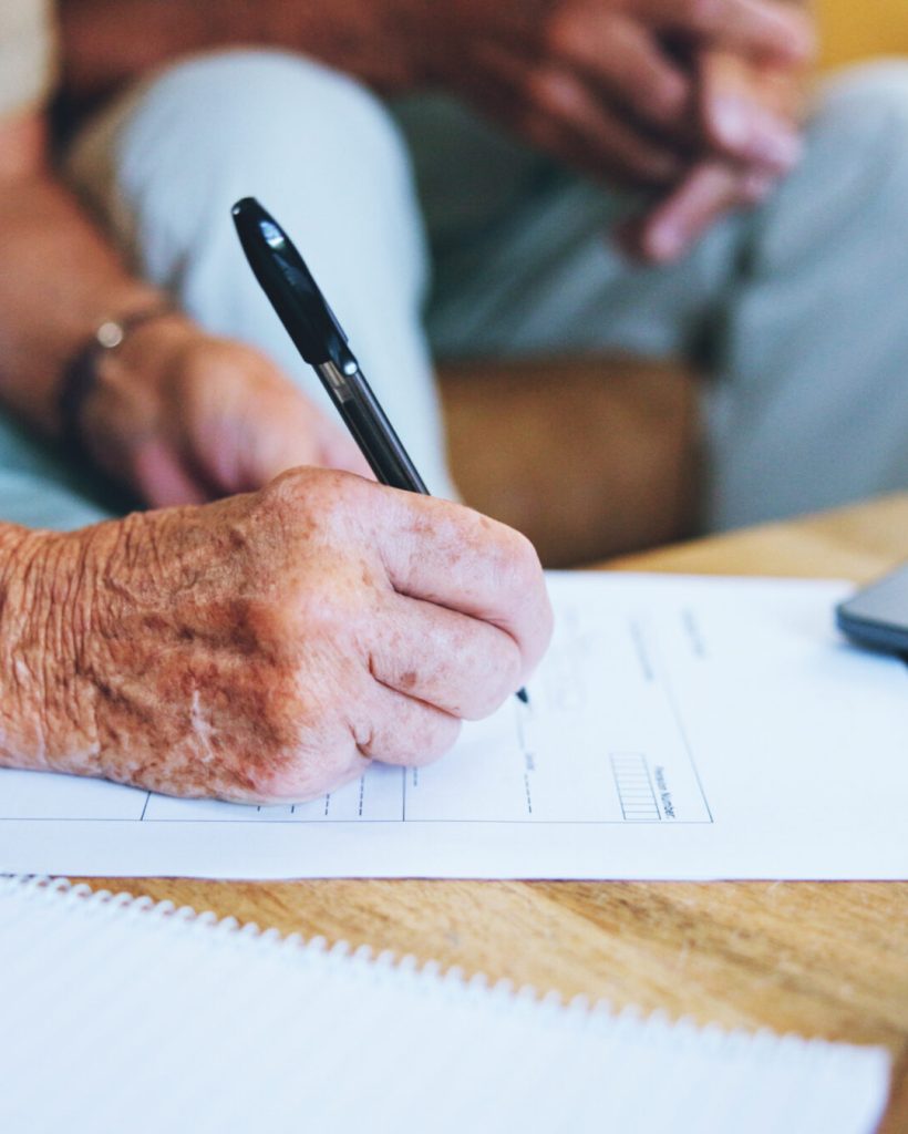 Senior man, paperwork and hands to sign or home for finance, life insurance and planning for assets.