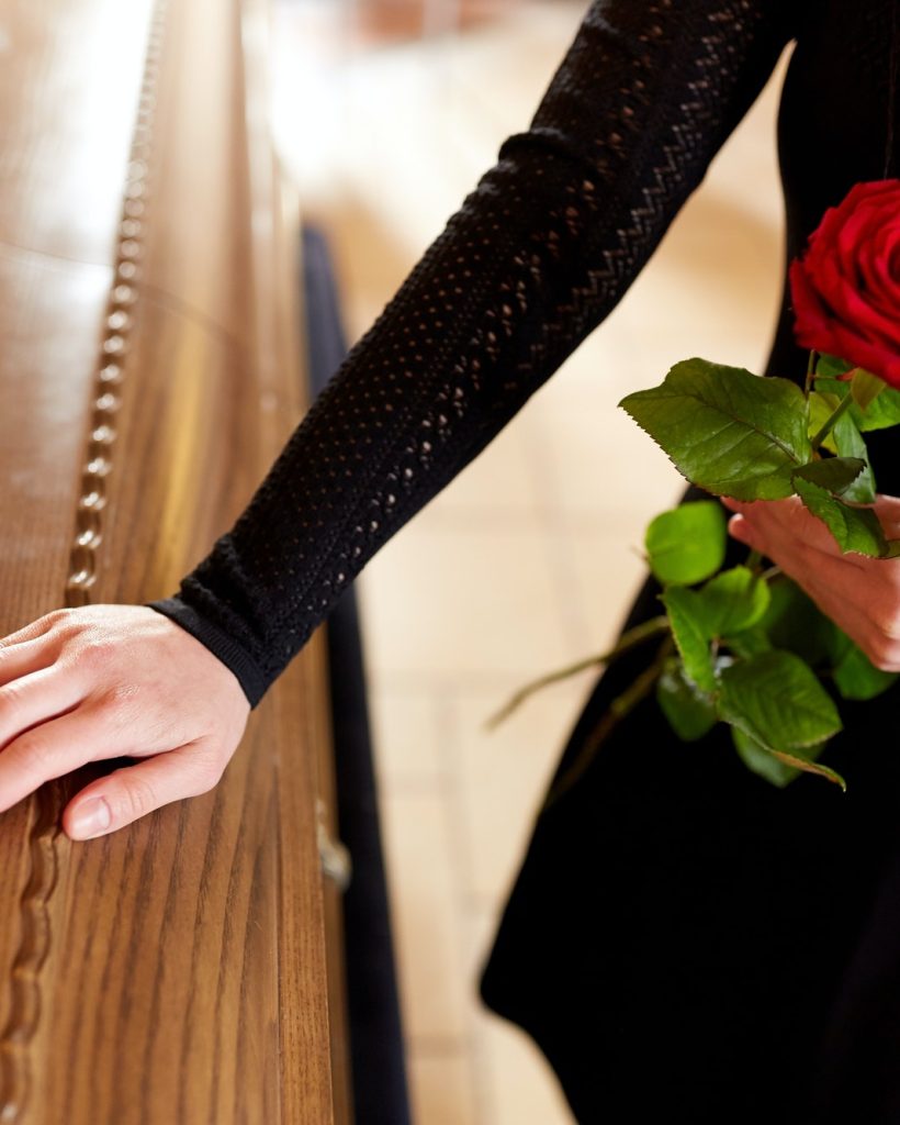 woman-with-red-roses-and-coffin-at-funeral-1.jpg
